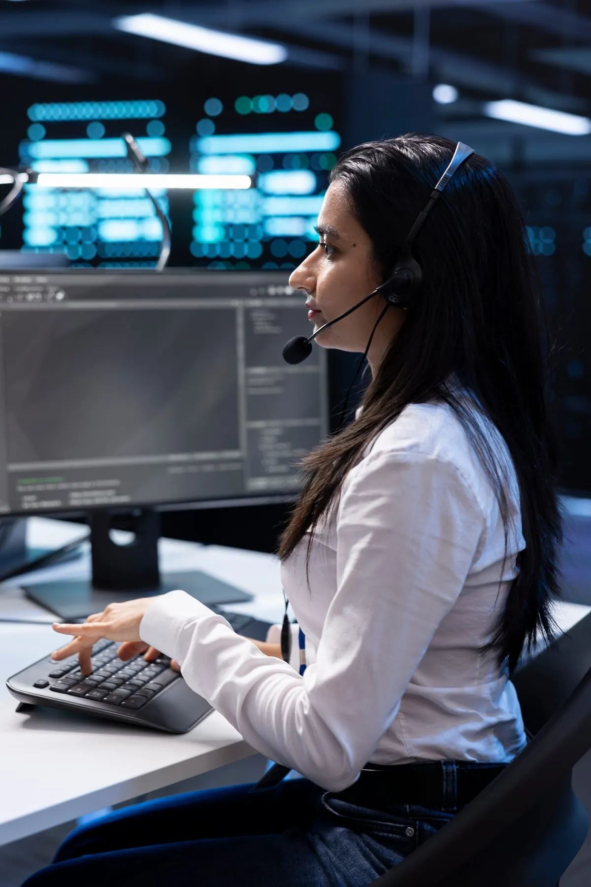 Operadora de la central receptora supervisando las cámaras de seguridad con auriculares